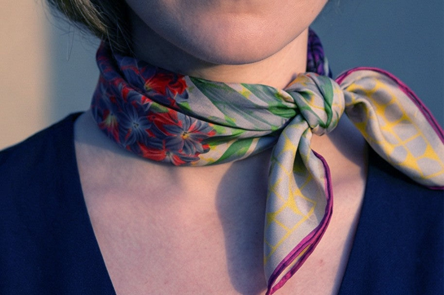 A Leeloo + Zohan printed silk scarf tied at the neck — styling detail.—Journal