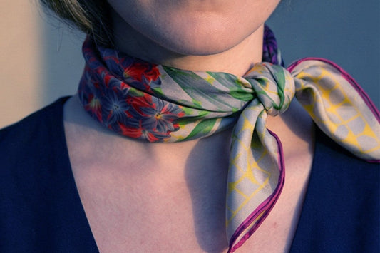 A Leeloo + Zohan printed silk scarf tied at the neck — styling detail.—Journal